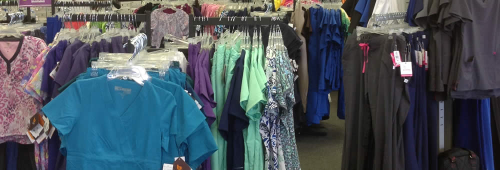 Scrub tops and pants on hangers in teal, purple, navy and grey at Simply Uniforms