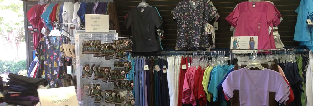 Wall display of scrub tops, pants and jackets at Simply Uniforms
